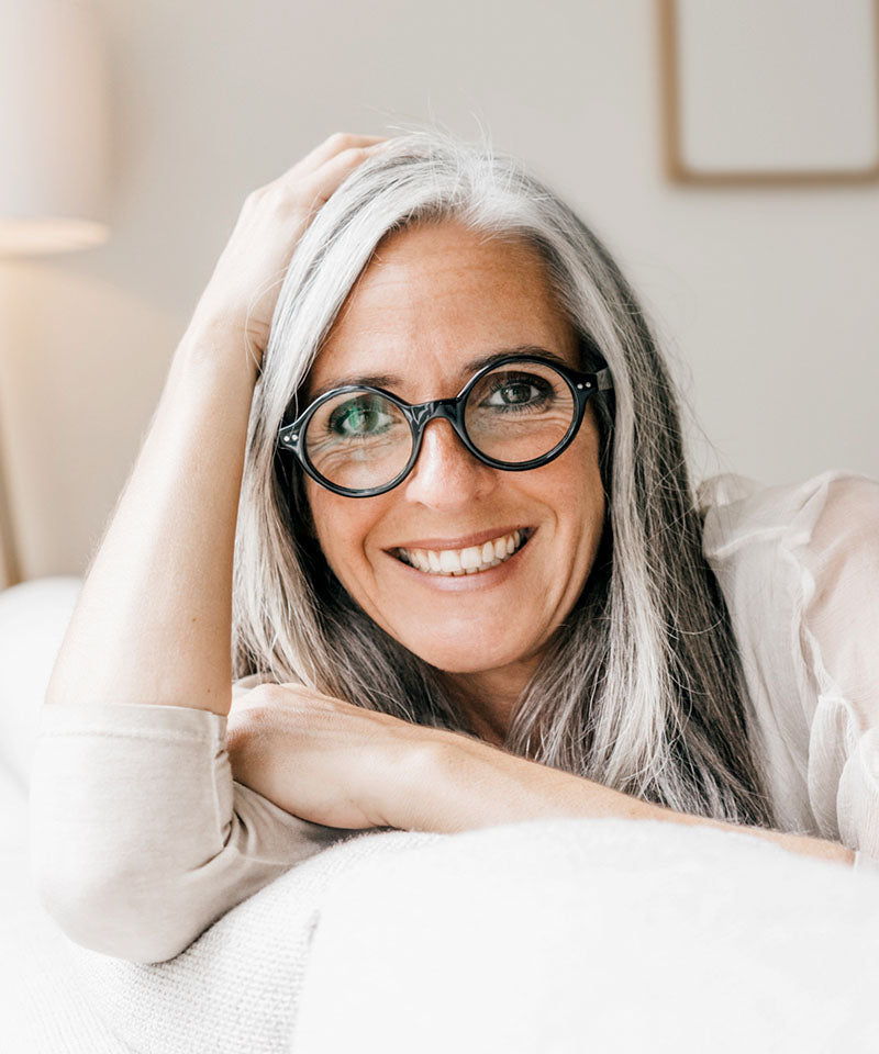 woman sitting on a white coach smiling